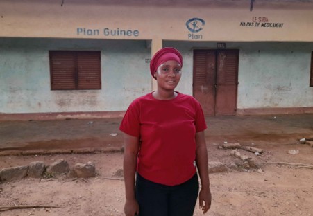 Femme en rouge devant un bâtiment Plan International